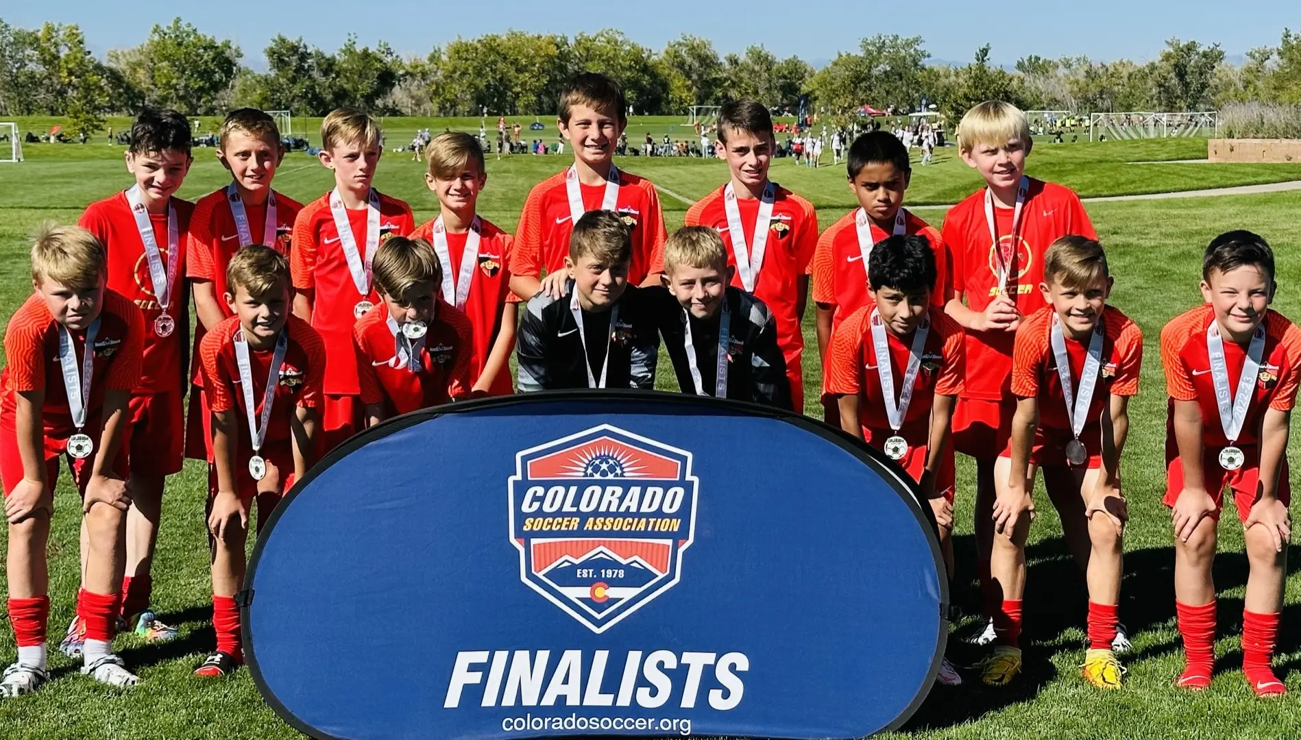 Real Colorado Academy team in red kits with silver finalist medals in front of Colorado Soccer Association Finalists banner September 2022